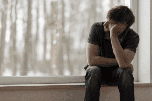 young man sitting alone in his room contemplating the 5 ways heroin can kill you