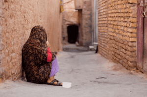 person huddled in back alley completely obscured by long shawl and living in one of the 5 countries with the worst drug problems
