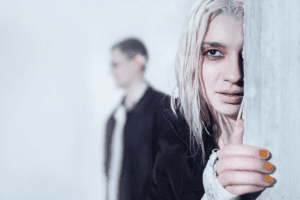 sickly looking woman clutching a door frame while an out of focus man stand behind her looking for ways to know if someone you know is using heroin