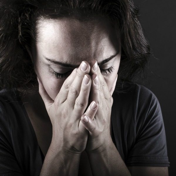 Worried woman with head in hands