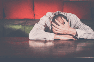 man passed out face down on kitchen table with hands covering his head displaying one of the 6 warning signs of alcoholism