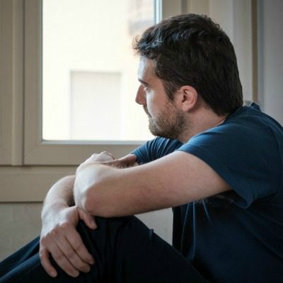 Man looking out of window thinking