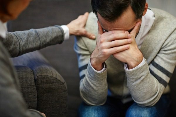 Counselor comforting male pattient