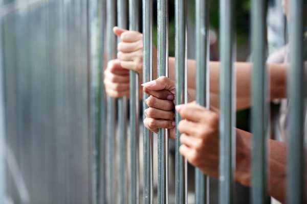Hands holding prison bars