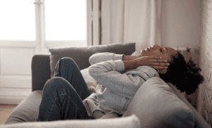 person laying on couch clutching their head wondering does morphine make pain worse