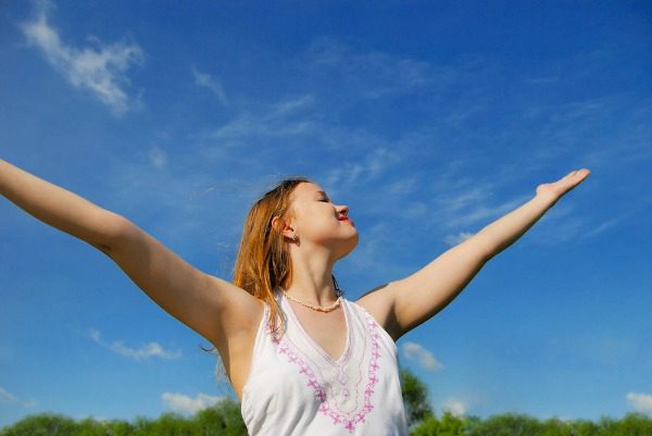 Happy unhibited woman stretching arms outdoors