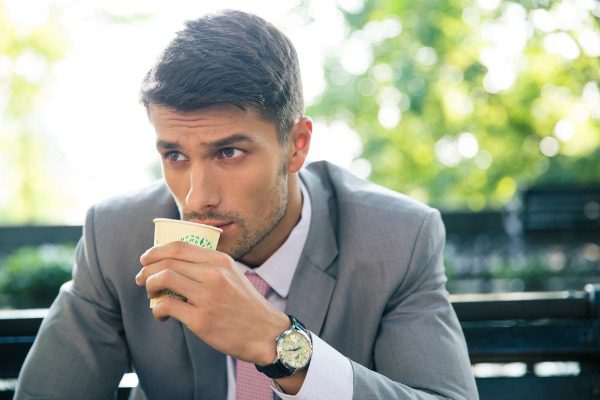 Man drinking coffee on a park bench