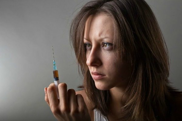 Woman holding heroin syringe