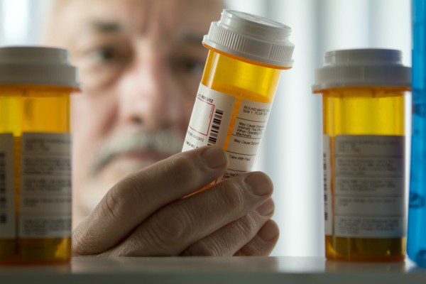 Elderly man holding pill bottle