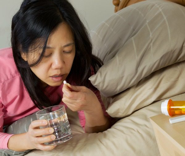 Woman taking pill in bed