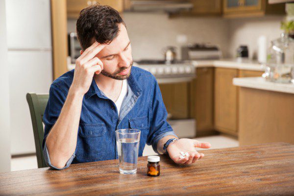 Distressed man holding pills
