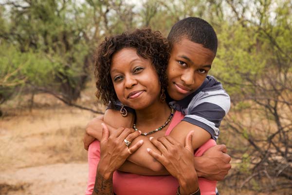 African American mother being hugged by son outside