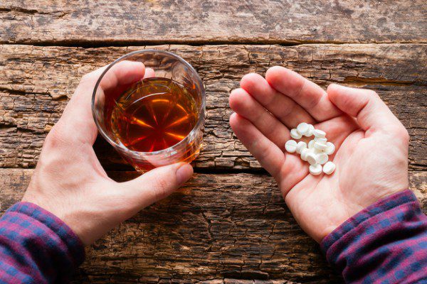 Man holding liquor and pills