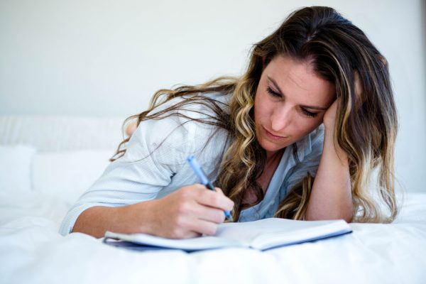 Woman on bed writing