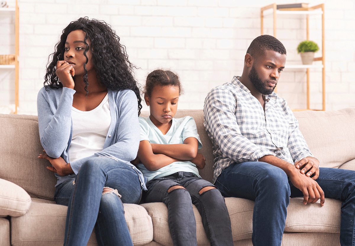 Family sitting together on a couch, appearing worried and emotionally distressed.