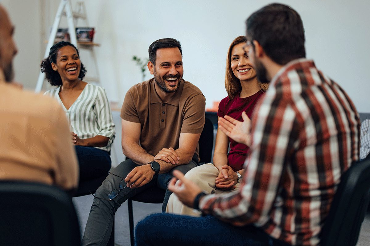 group members in therapy session sit in a circle and laugh with each other after discussing tips for alcohol rehab