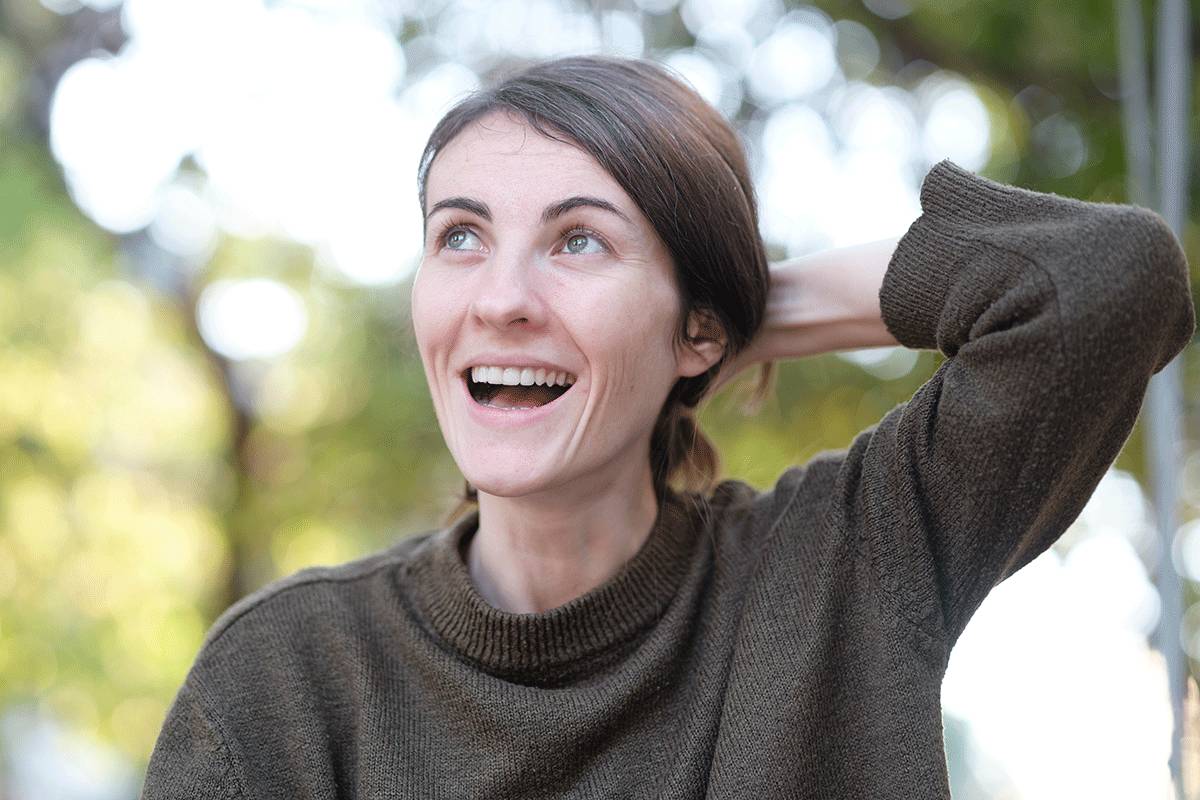 woman holds her hair and is excited while enjoying her life after rehab