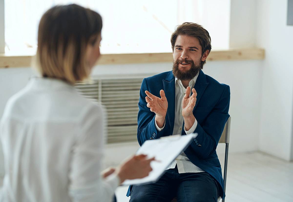 A man claps while listening to his therapist tell him the cost of alcohol rehab is covered by his insurance