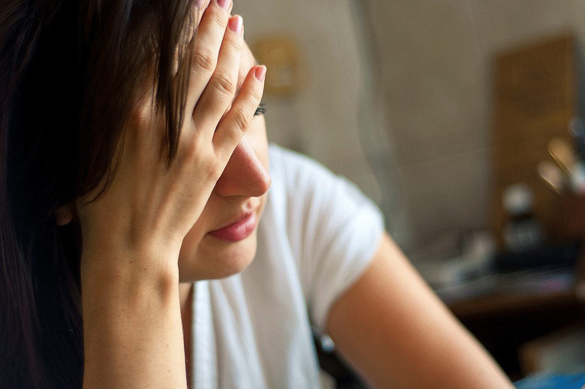 Struggling woman sits with her hand to her head wondering what to expect during detox