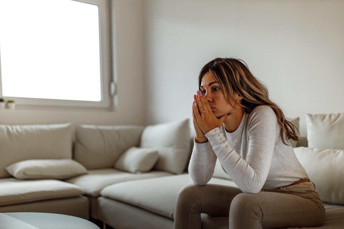 woman sits and leans forward on her couch while asking herself how do you know when you are close to greening out