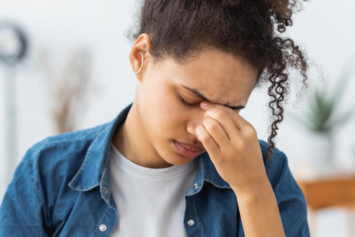 distraught woman holds her nose with her fingers while struggling with signs of stimulant abuse
