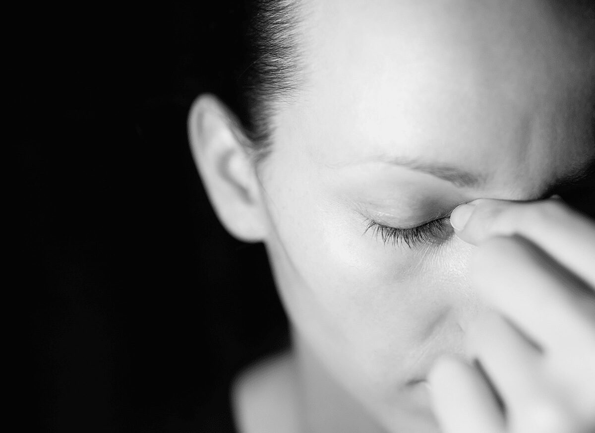 woman holds her hand to the bridge of her nose struggling with the realization of floricet withdrawal symptoms
