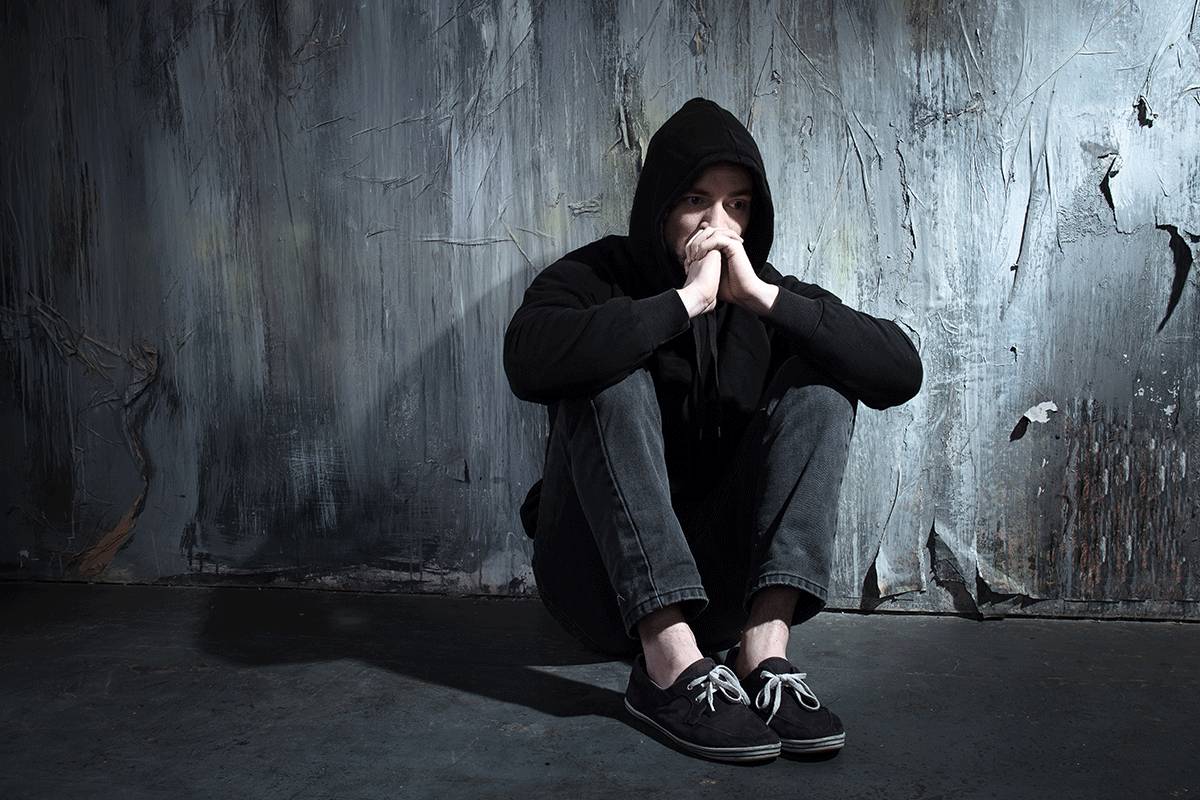 man in hoodie sits on floor and leans on wall holding his hands to face and wonders is floricet addictive