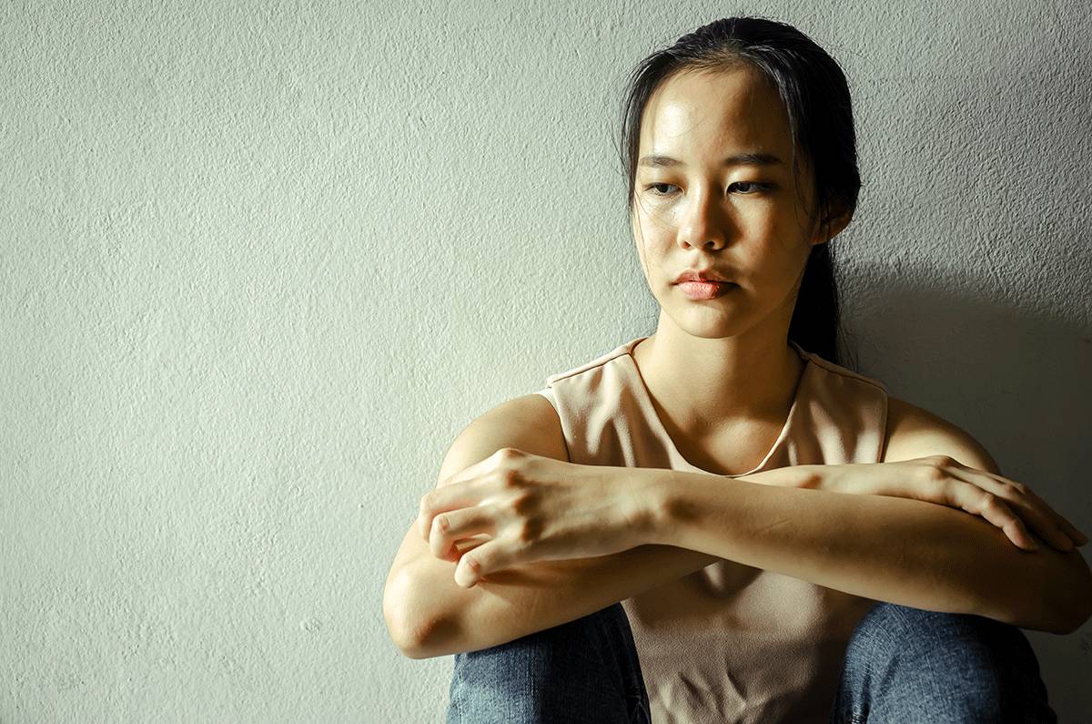 woman sits on ground and leans against a wall looking afar wondering is librium addictive