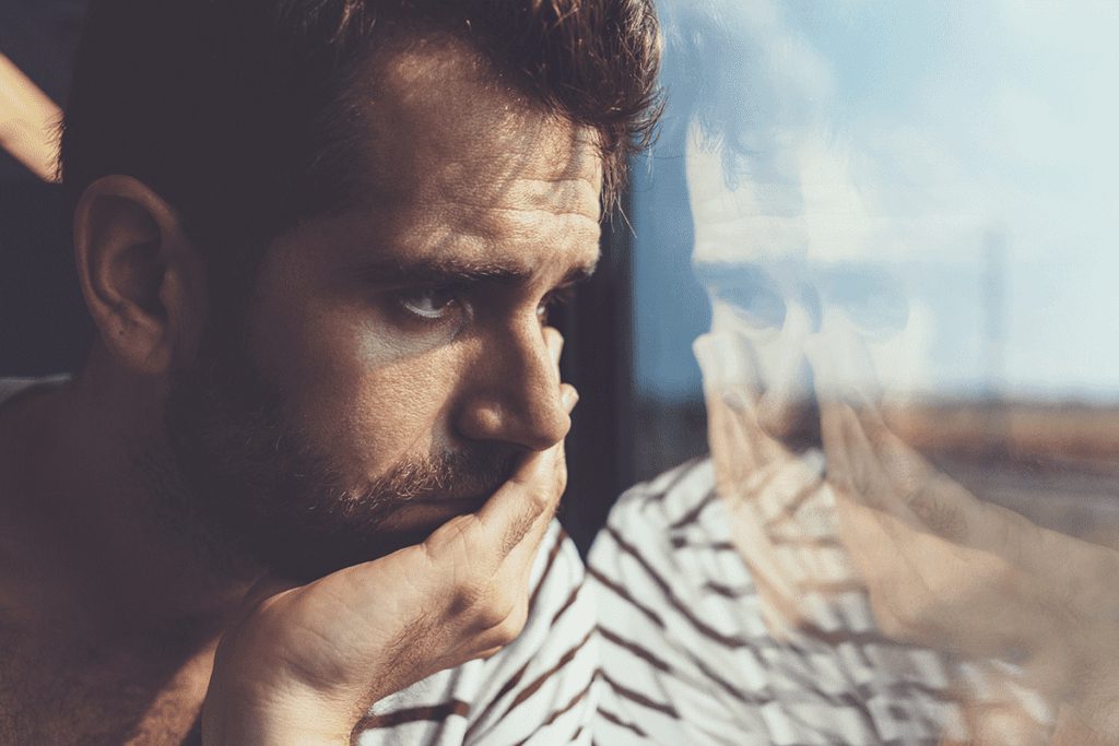 Man holds his hand to his mouth and looks out a window wondering what is flakka
