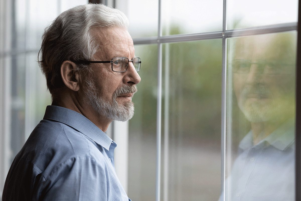 Older man with glasses looks out the window and wonders what is wet brain