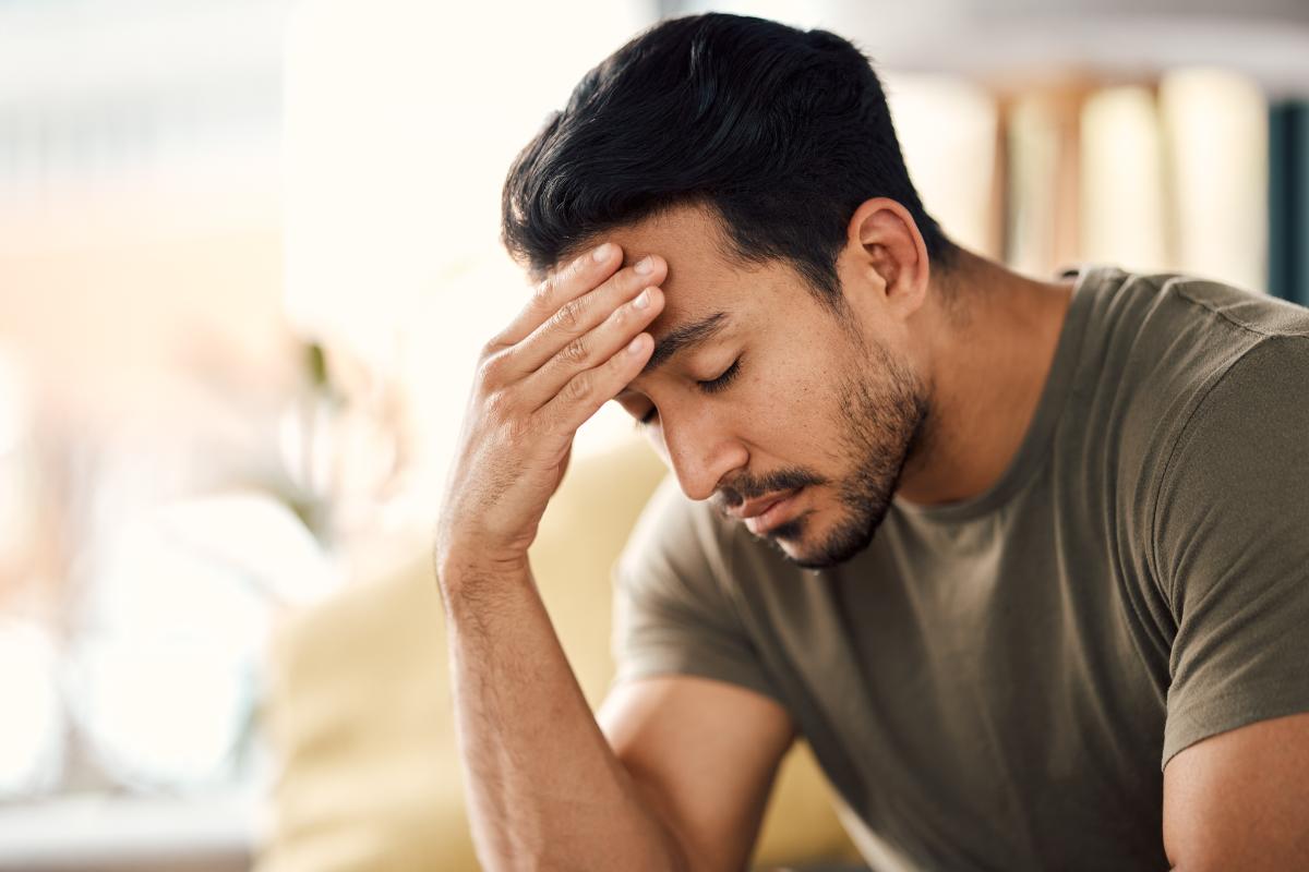 Man leans his head down on his hand while thinking about dry drunk symptoms