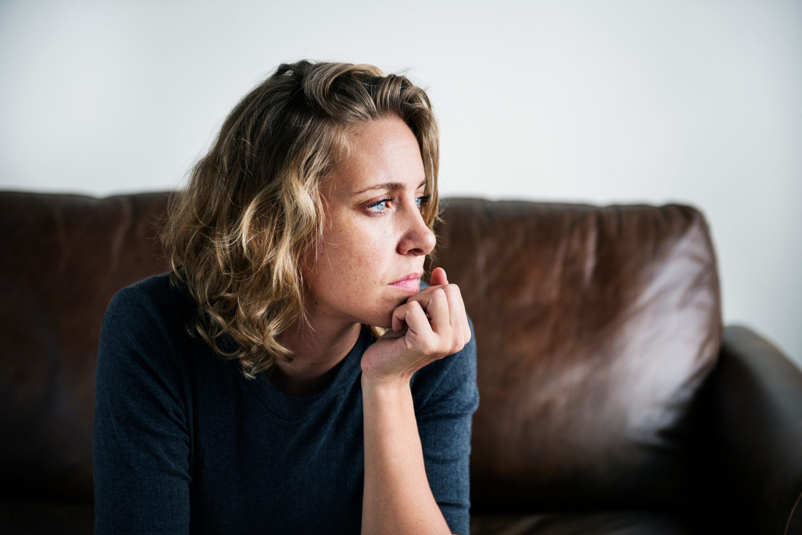 blonde woman sits on a couch and looks to her side and wonders what are the signs of gas station heroin addiction