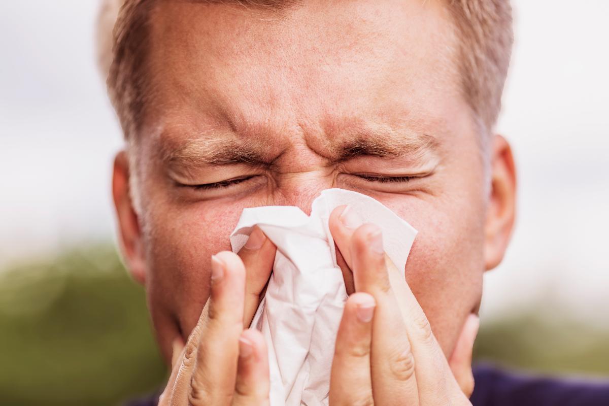 man blows his nose with a tissue while thinking about what is huffing