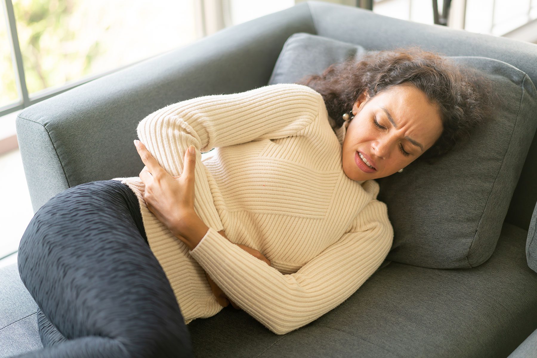 woman holds her stomach in pain and asks herself what are the signs of kratom withdrawal