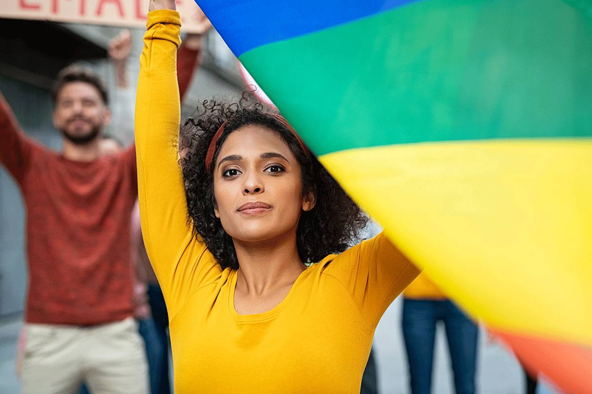 young woman waving rainbow flag representing drug addiction help for the LGBTQ community.